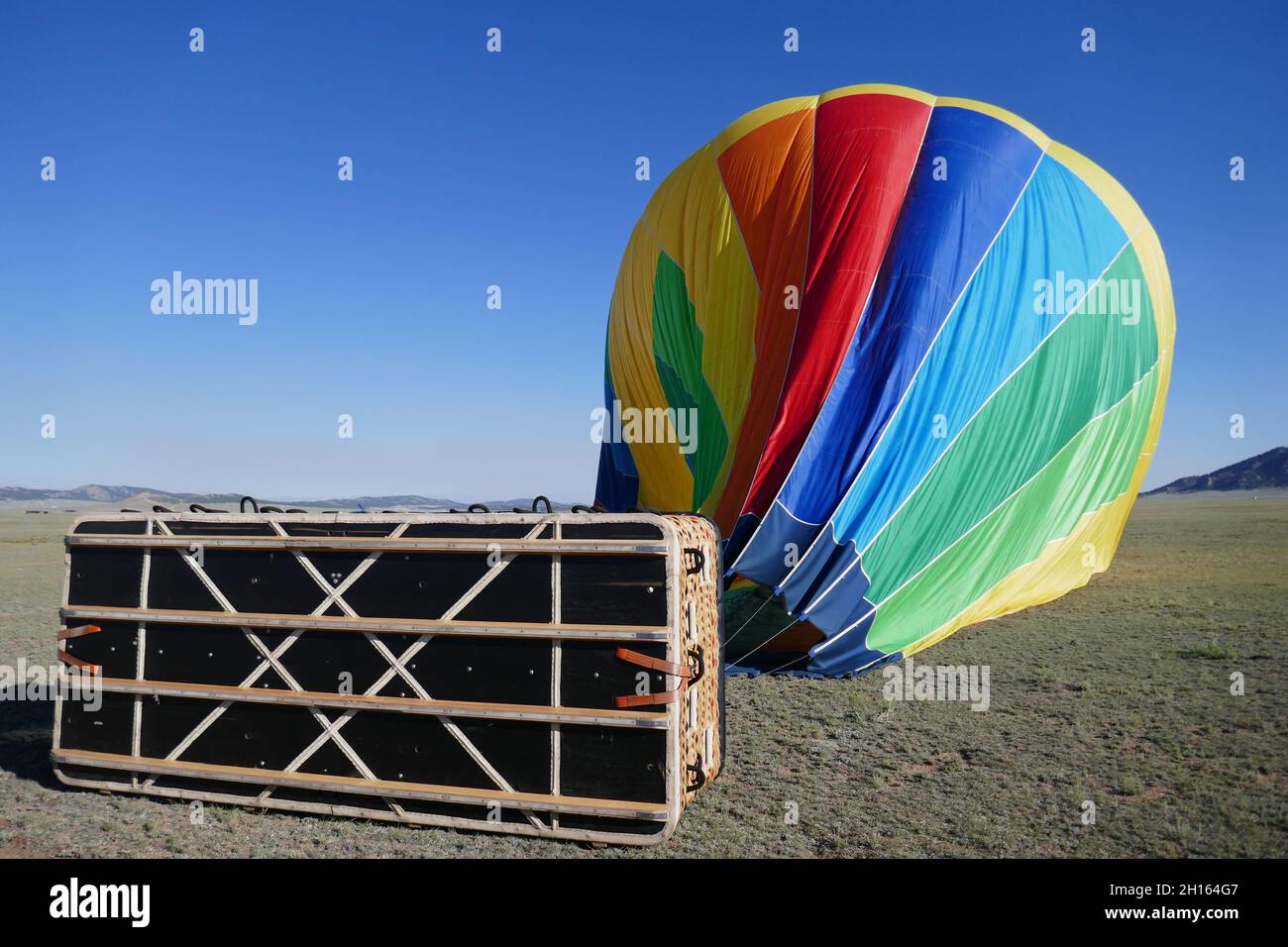 Colorful hot air balloon deflating on ground after flight with gondola