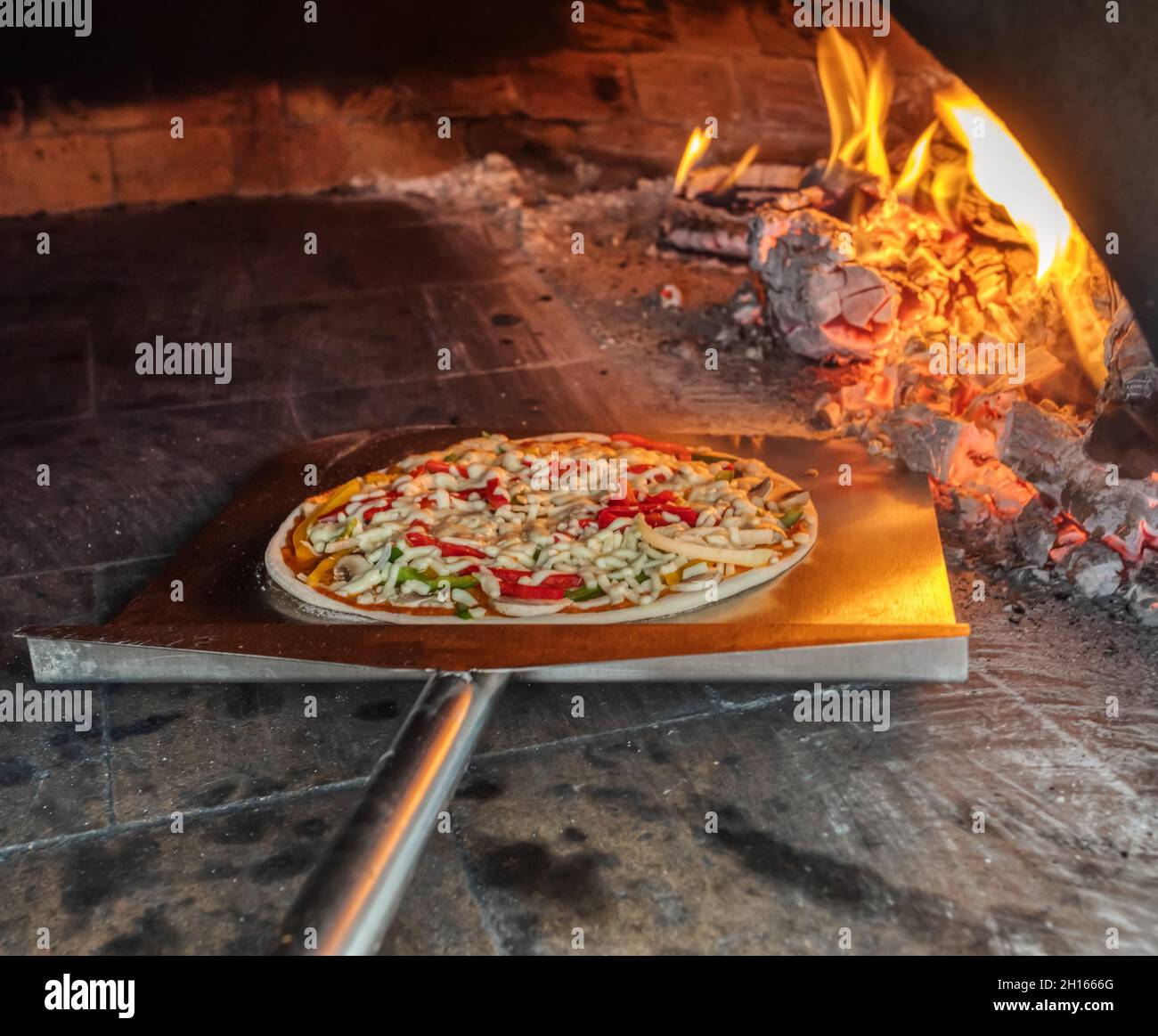 Pizzeria putting the pizza in the wood fired oven Stock Photo