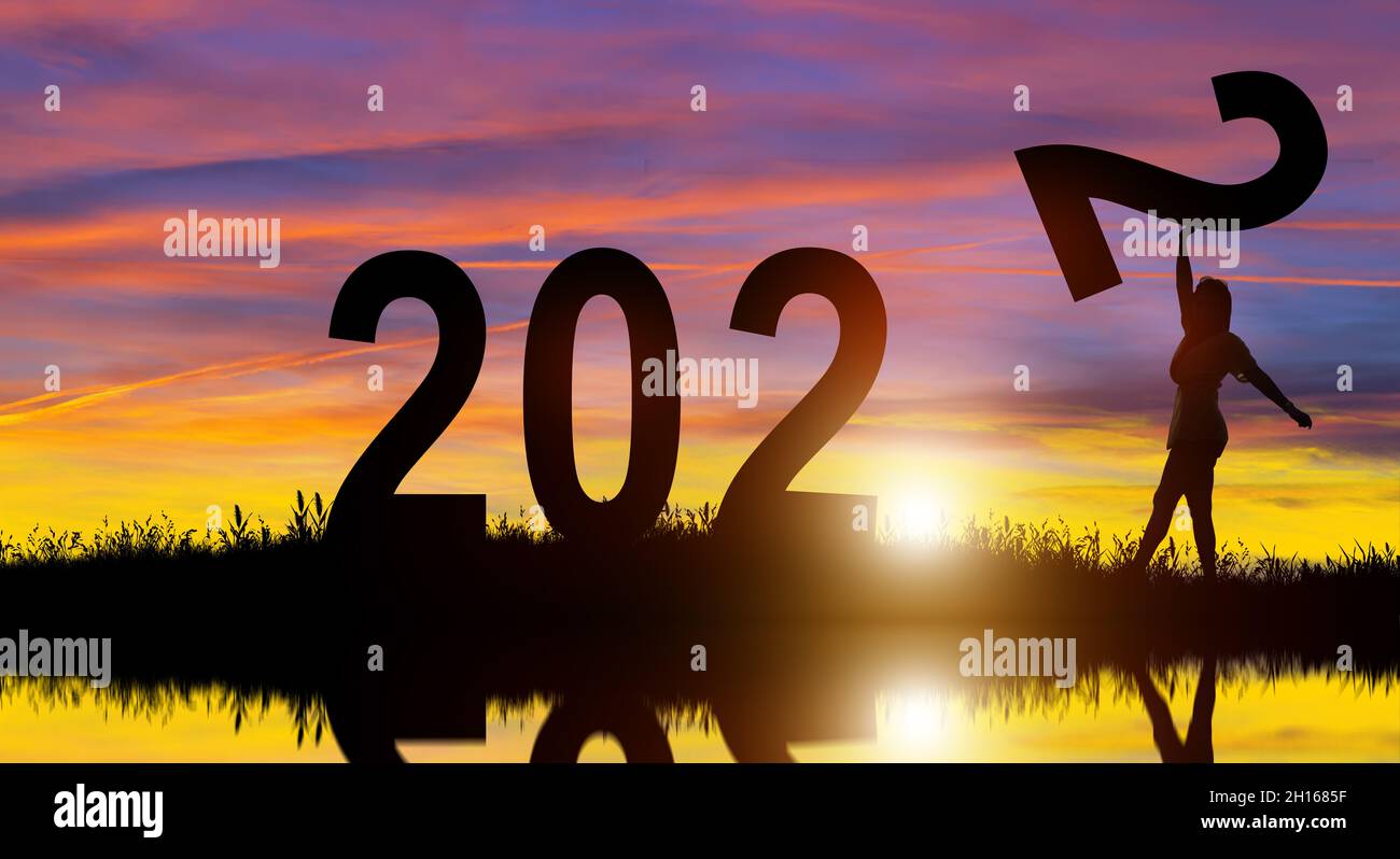 Silhouette women holding number 2 on the hill while celebrating 2022 years in the sunrise background. Merry Christmas and Happy New Year. Stock Photo