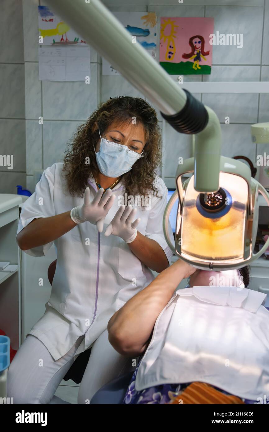 South American dentist checking up the teeth of a middle age Caucasian woman Stock Photo