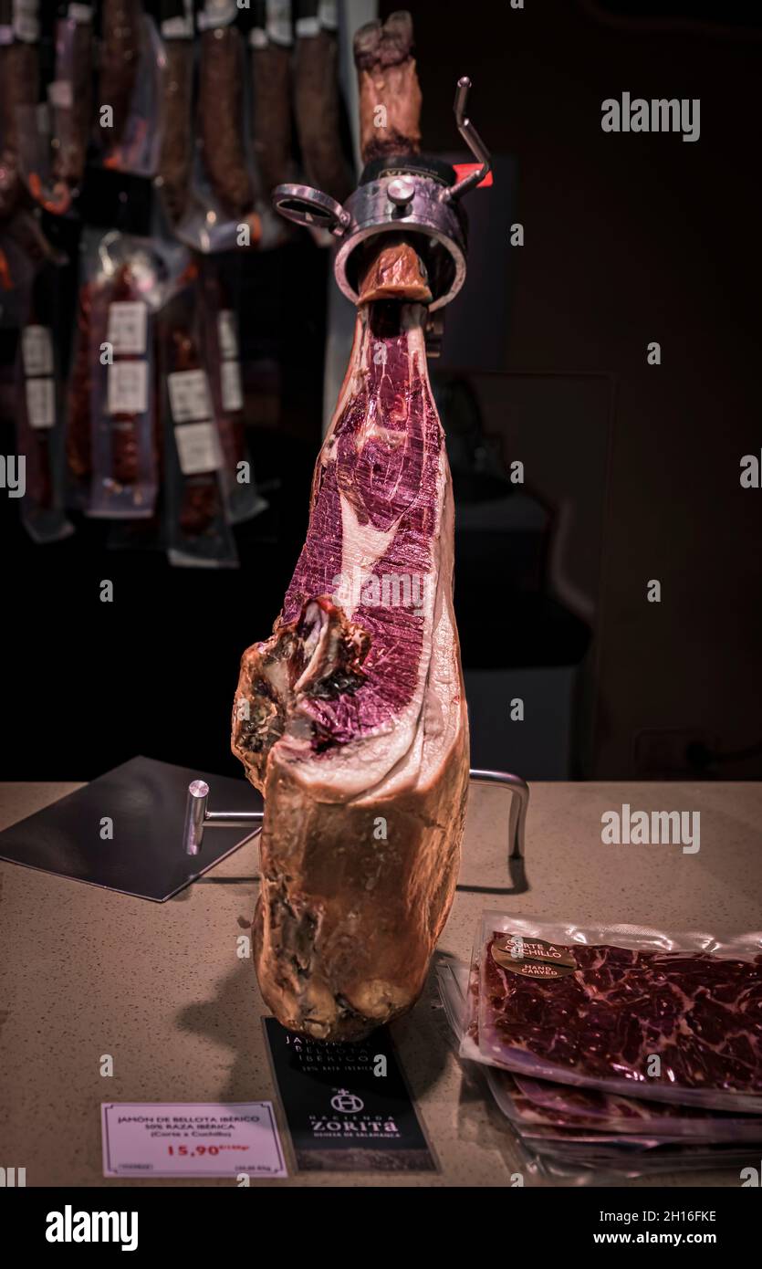 Pamplona, Spain - June 22 2021: Whole bone-in leg of Spanish serrano iberico ham on a carving stand at a local butcher shop in old town or Casco Viejo Stock Photo