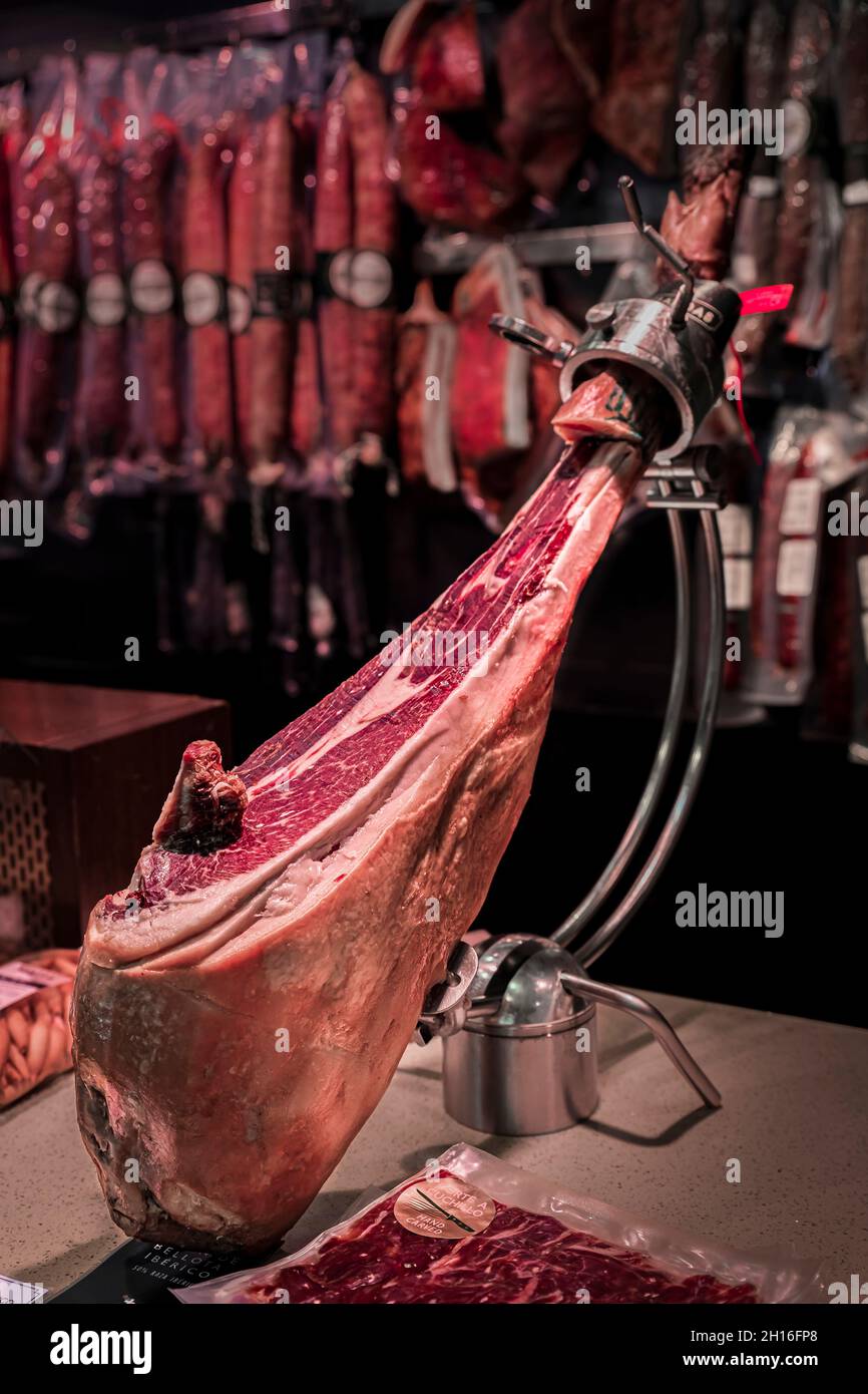 Whole bone-in leg of Spanish serrano iberico ham on a carving stand at a local butcher shop in the old town or Casco Viejo in Pamplona, Spain Stock Photo