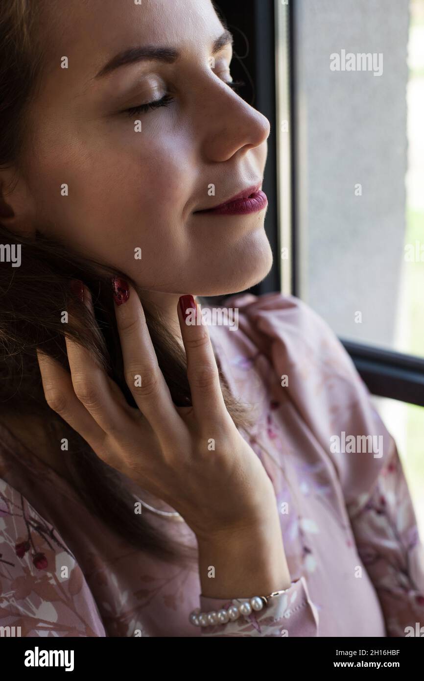 Beautiful young woman in pink dress sits on the windowsill Stock Photo ...