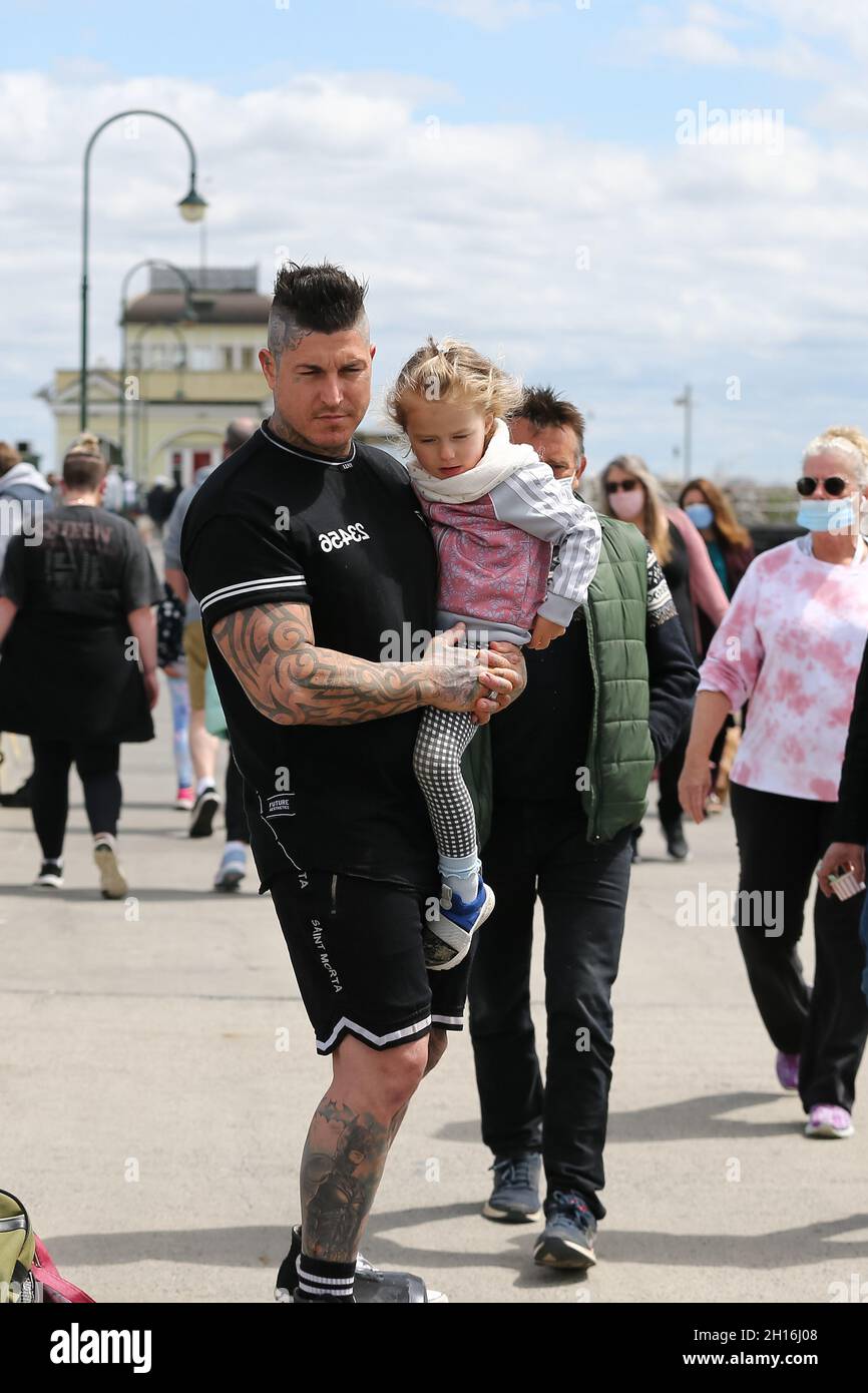 Melbourne, Australia. 17th Oct, 2021. A man carries his daughter as he