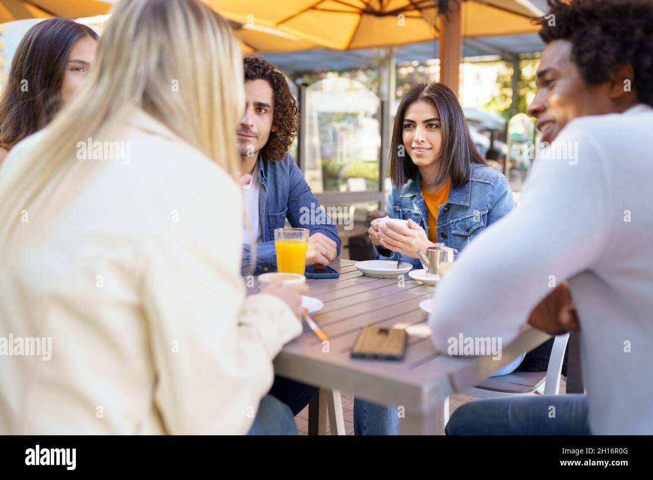 Multi-ethnic group of friends having a drink together in an outdoor bar ...
