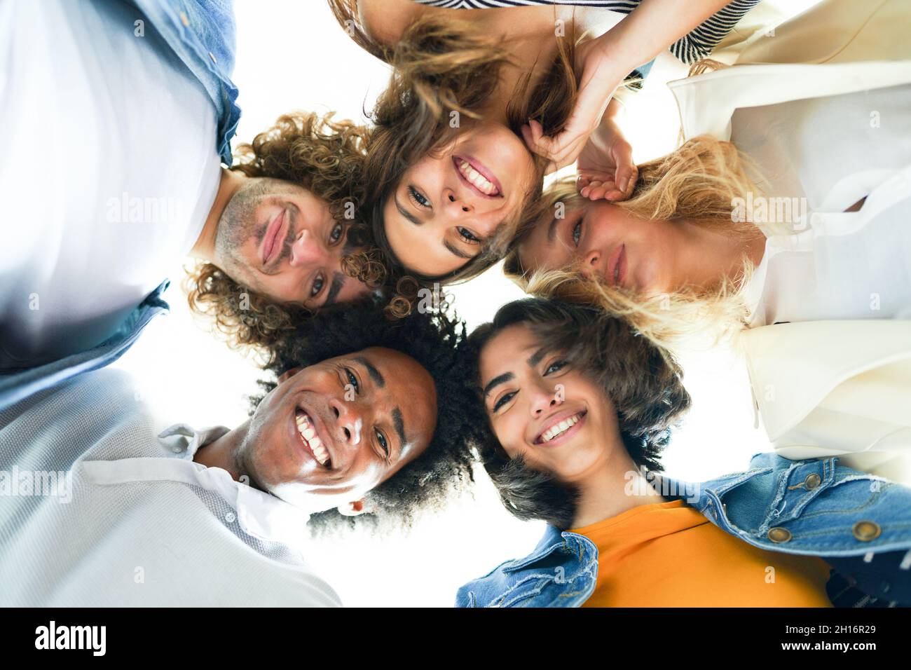 Multi-ethnic group of friends with their heads together in a circle. Stock Photo