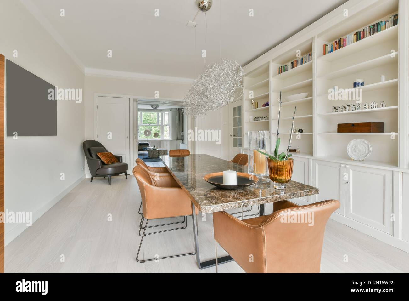 Long table and leather chairs located near shelves with decorations and ...