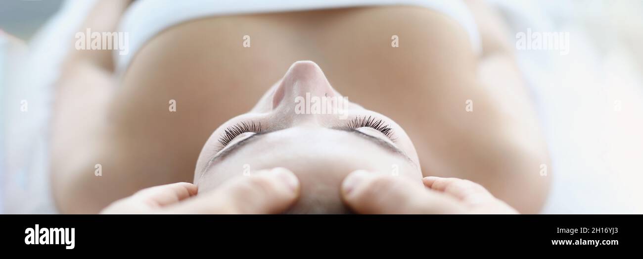 Young woman masseur makes face and head massage in spa salon Stock Photo