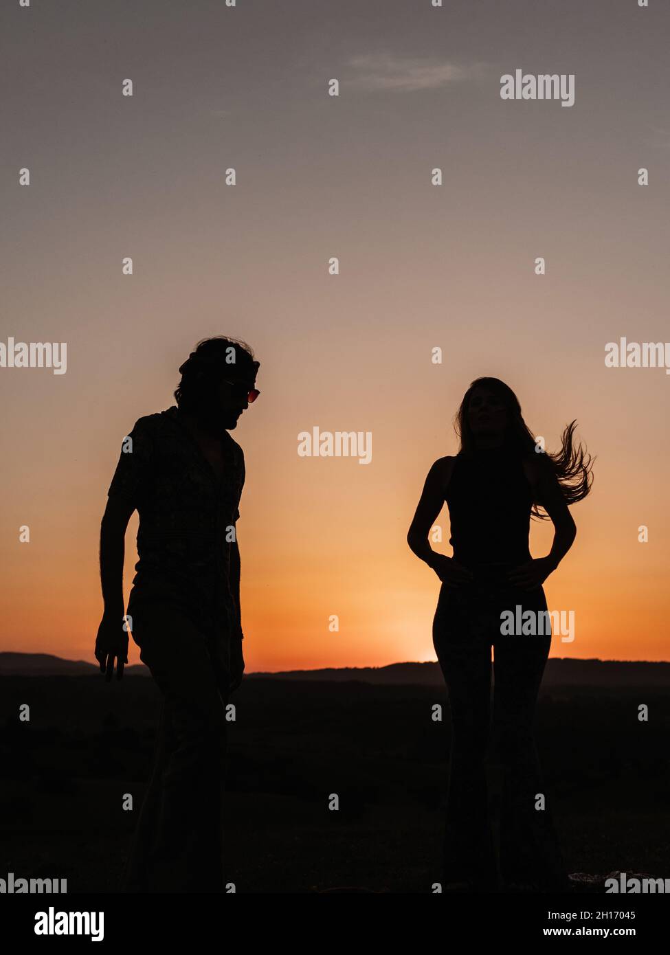 Silhouettes of a couple dancing in nature while the sun hides in the ...