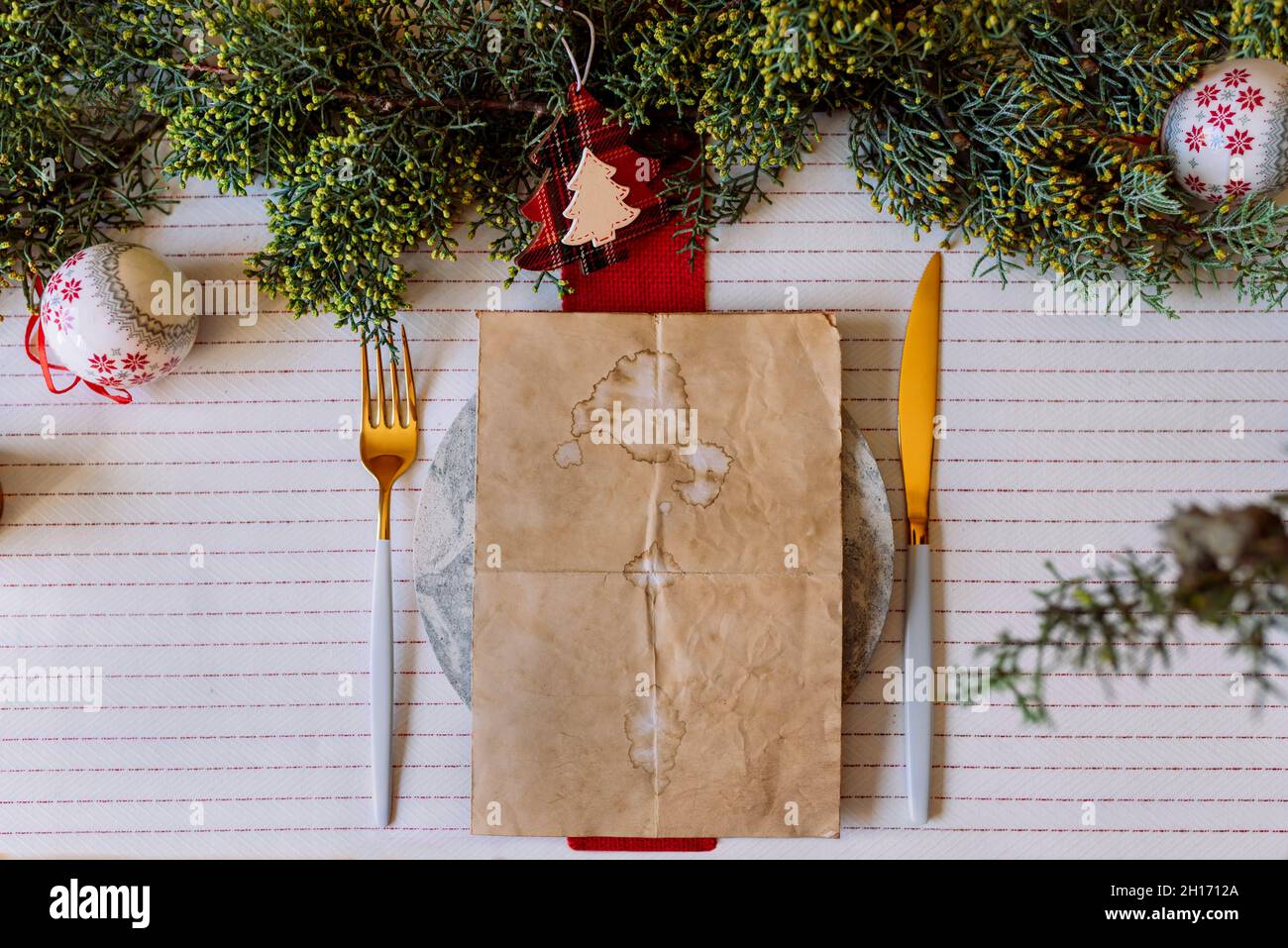 From above red holiday place setting with empty menu on white tablecloth Stock Photo