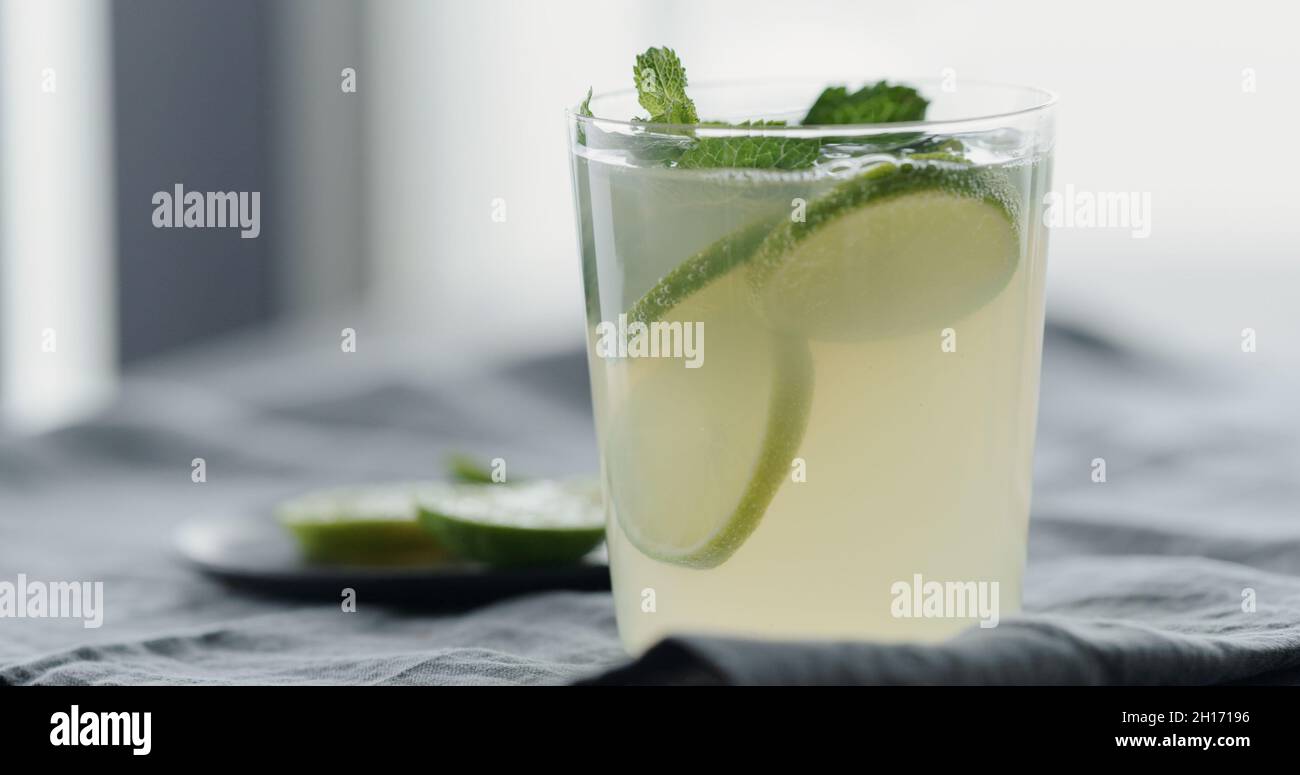 decorate lemonade with mint leaves in tumbler glass on linen cloth