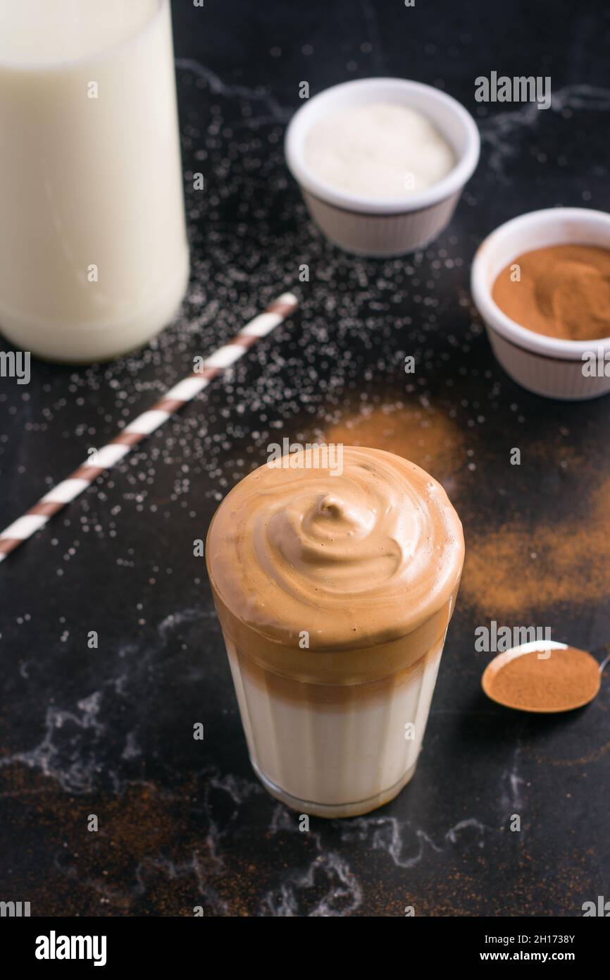 Glass of delicious Dalgona coffee with milk and foamy topping placed on