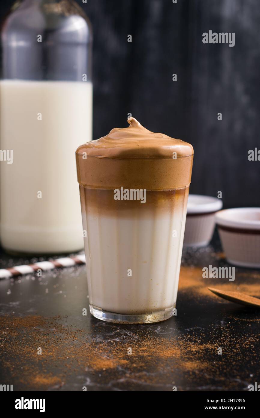 Glass of delicious Dalgona coffee with milk and foamy topping placed on