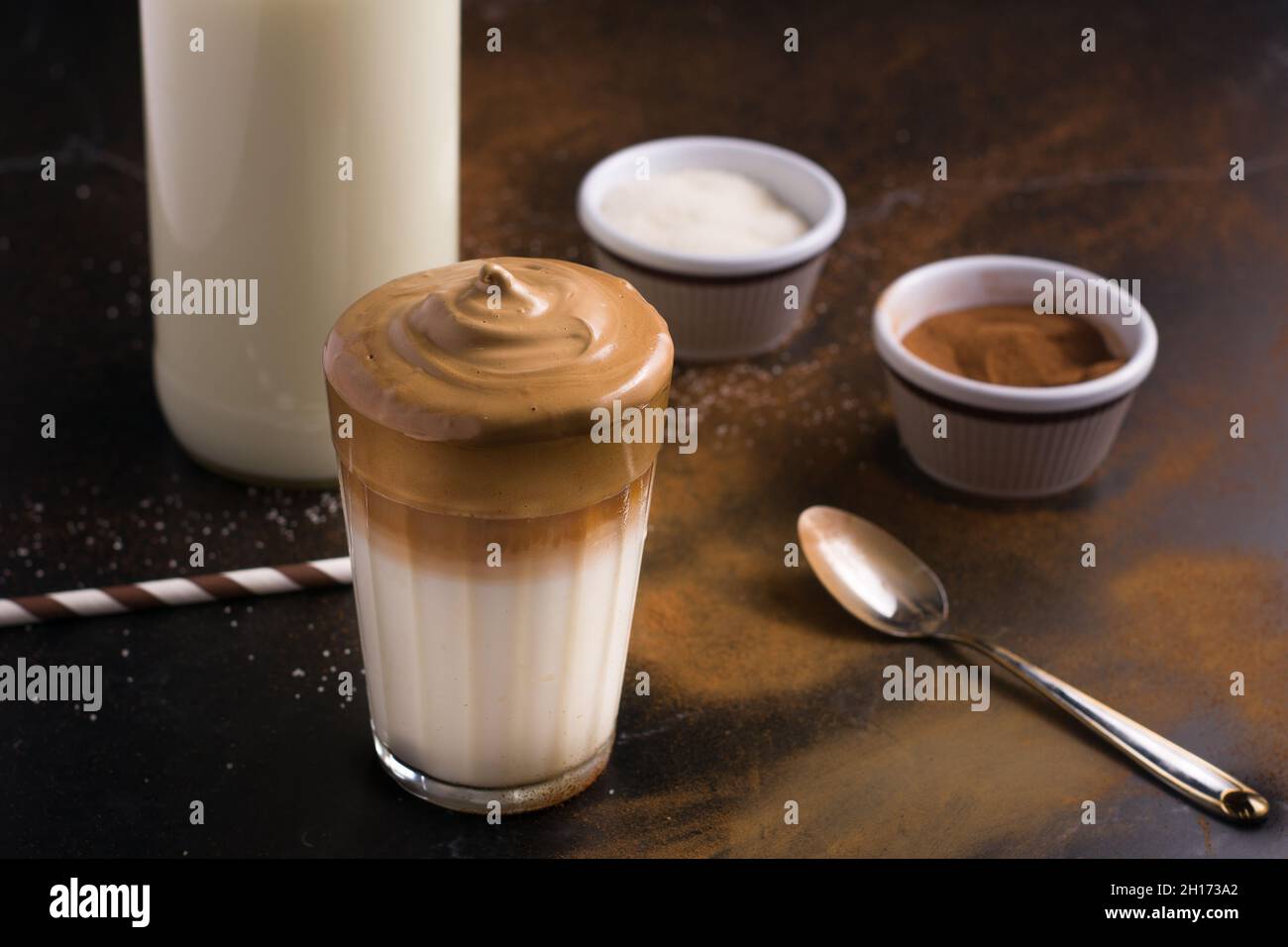 Glass of delicious Dalgona coffee with milk and foamy topping placed on