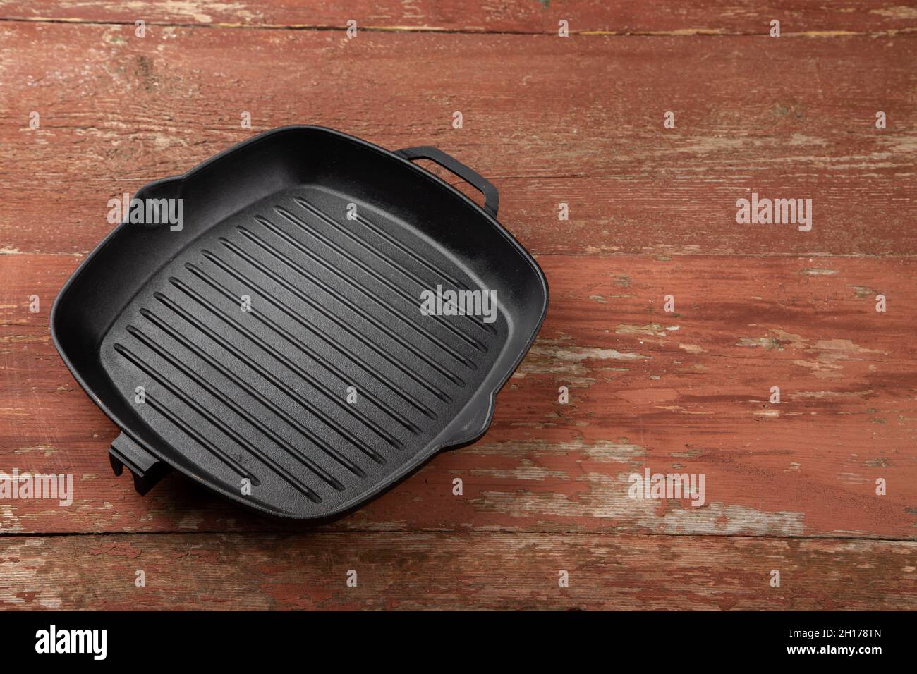 https://c8.alamy.com/comp/2H178TN/an-empty-black-cast-iron-grill-pan-for-cooking-delicious-meat-wood-background-space-for-text-top-view-2H178TN.jpg