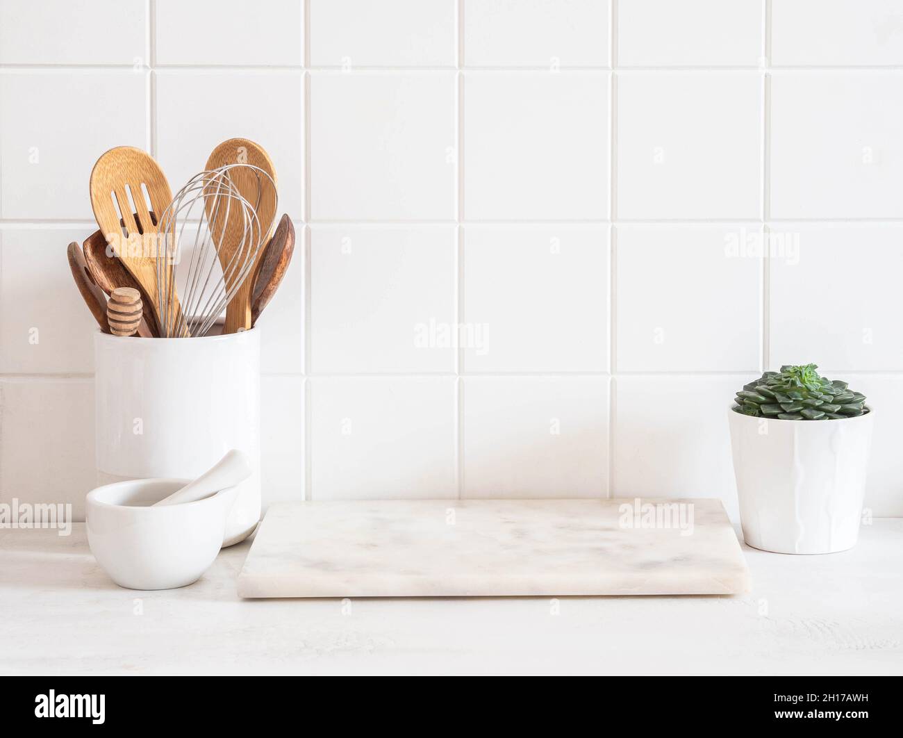Stylish white kitchen background with kitchen utensils and green