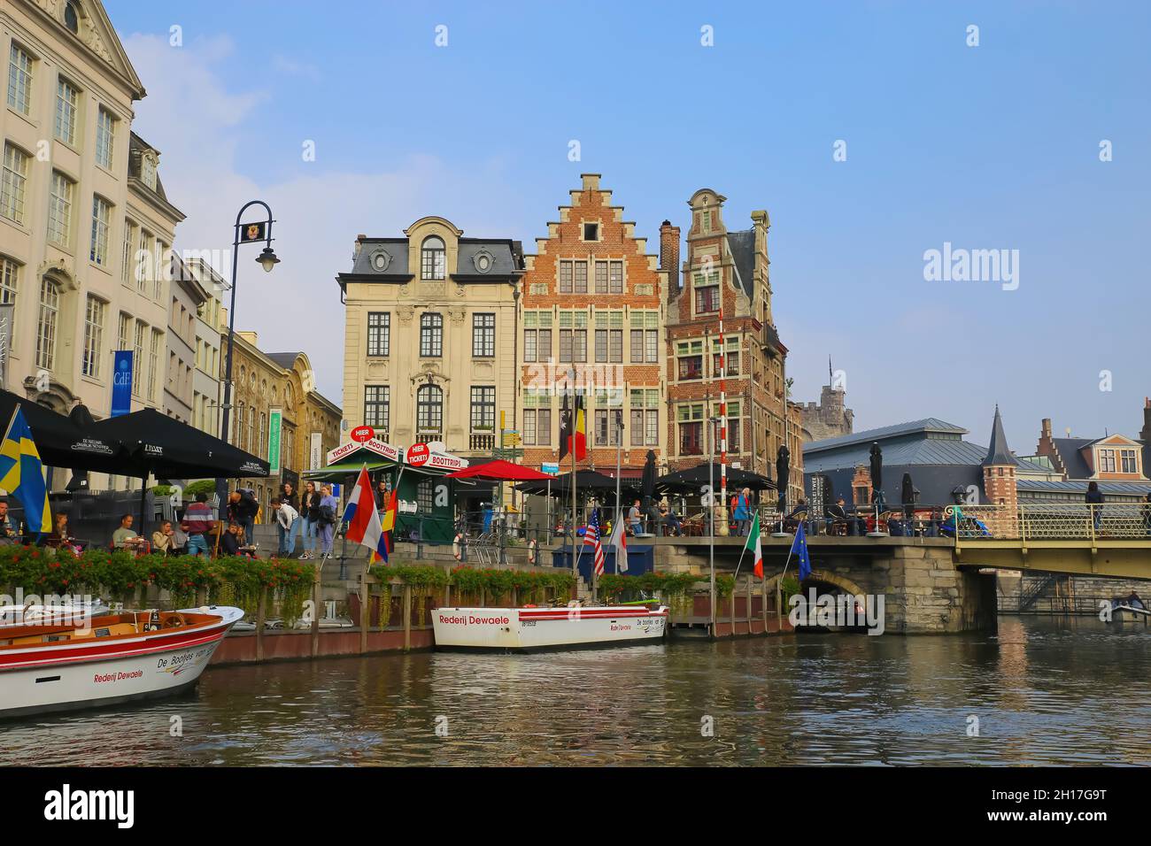 Gent (Grasbrug), Belgium - October 9. 2021: View over water canal on exterior cafe, sightseeing boat tour pier, medival buildings and bridge in the mo Stock Photo