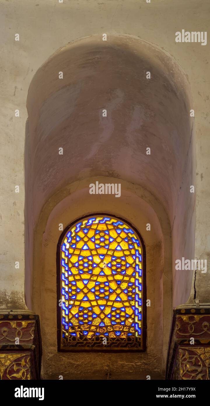 Recessed Perforated stucco window decorated with colorful stain glass with geometrical circular patterns and floral patterns, at Mamluk era public historical Qalawun complex, Moez Street, Cairo, Egypt Stock Photo