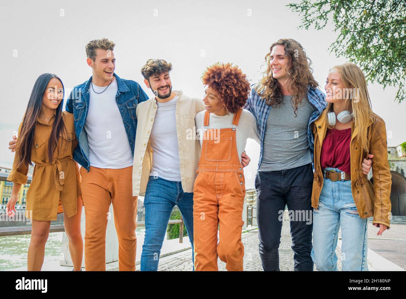 Group of happy teenage friends walking along the city street and talking - University students walking together and have fun - Tourism, travel and lei Stock Photo