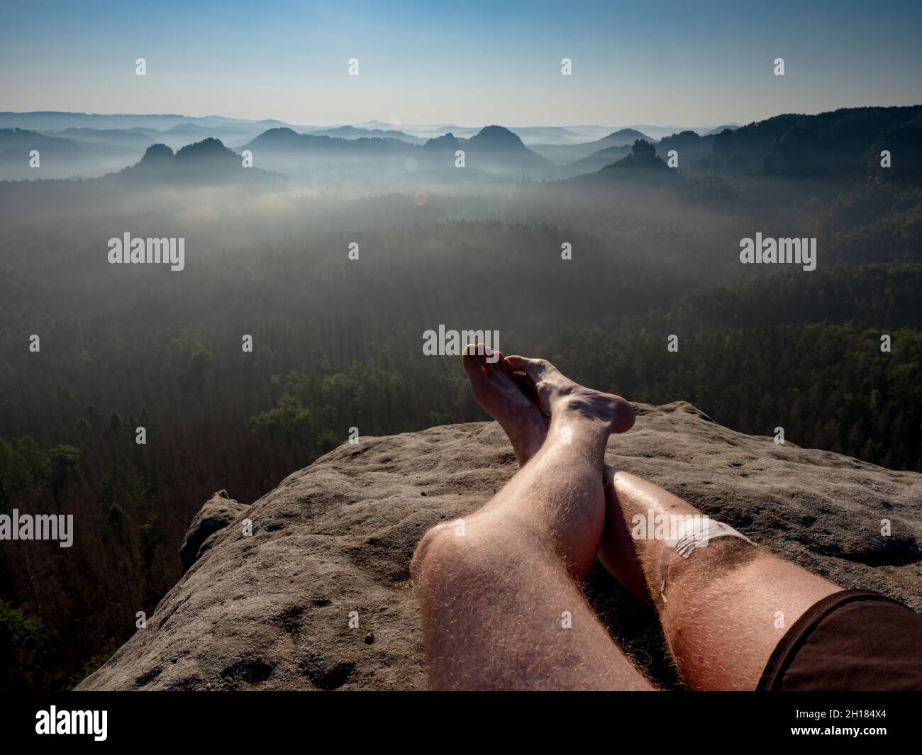 Crossed male barefoot legs of man relax on mountain summit. Hiker lay down and have a rest Stock Photo