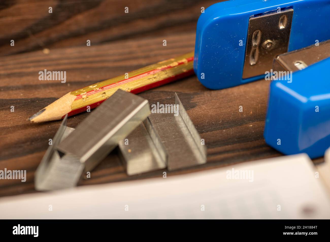 Office stapler, stapler staples and white paper on the table, close-up, selective focus Stock Photo
