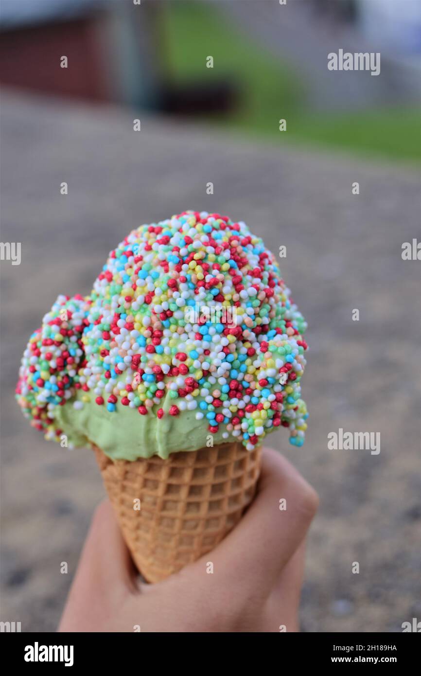 Ice cream with colorful sugar sprinkles in hand as a close-up Stock Photo