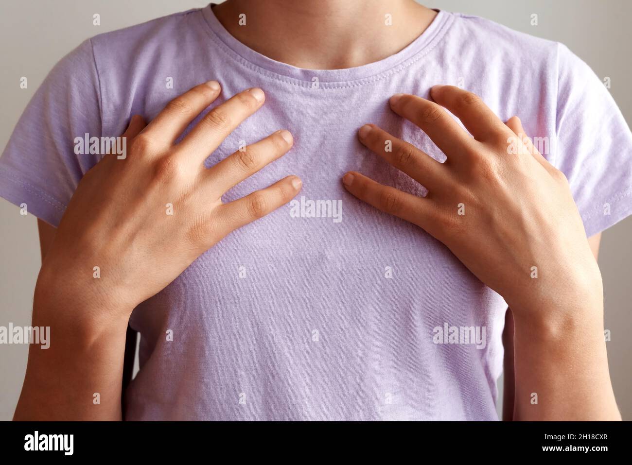 Teenage girl practicing EFT or emotional freedom technique,  tapping on the collarbone point Stock Photo