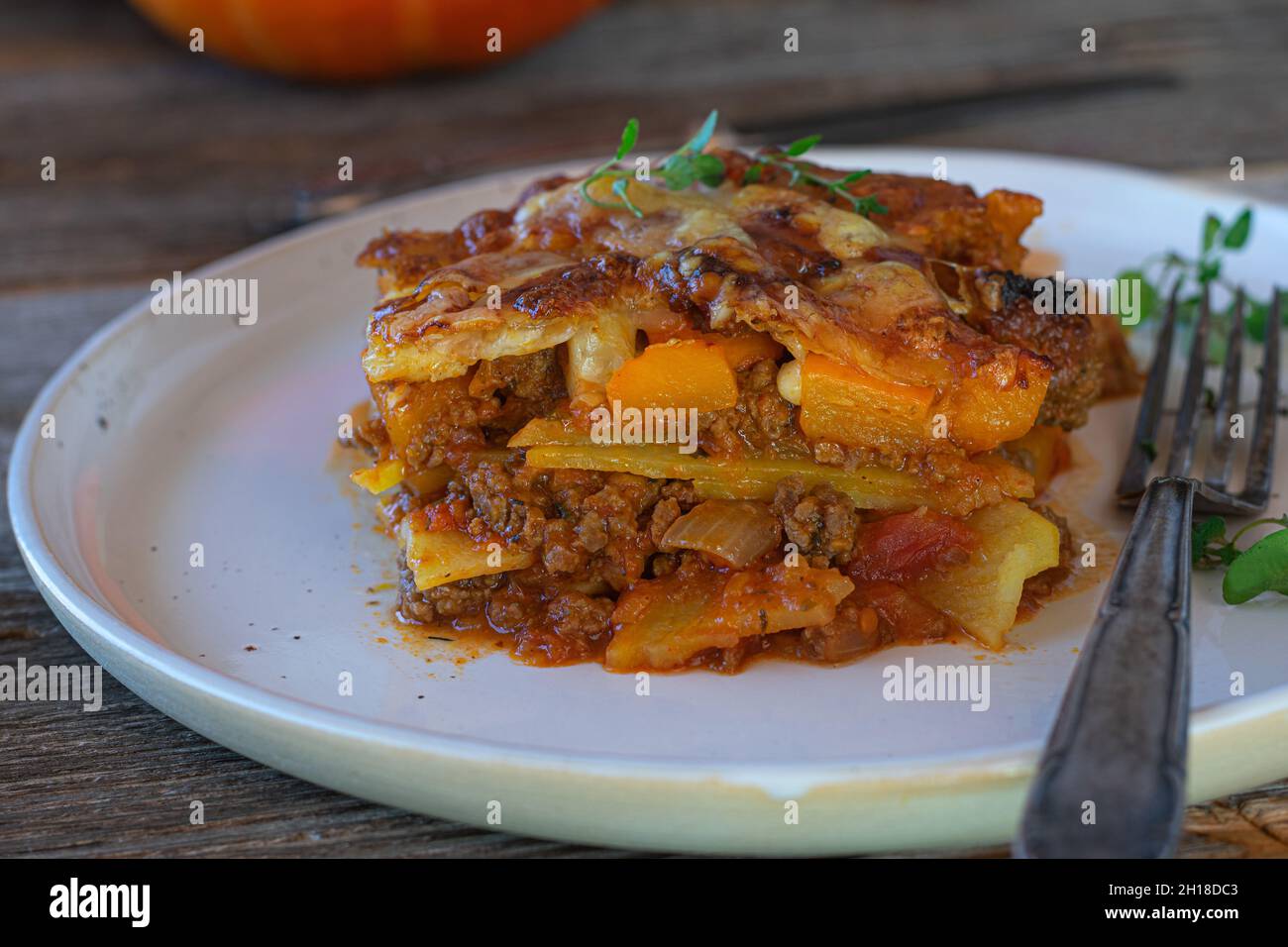 gluten free casserole dish with ground beef, potatoes and hokkaido pumpkin. Topped with melted mozzarella cheese and served on plate with fork Stock Photo