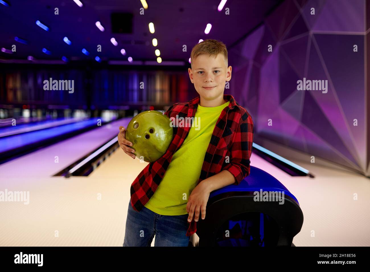 Boy with ball poses at the lane in bowling alley Stock Photo