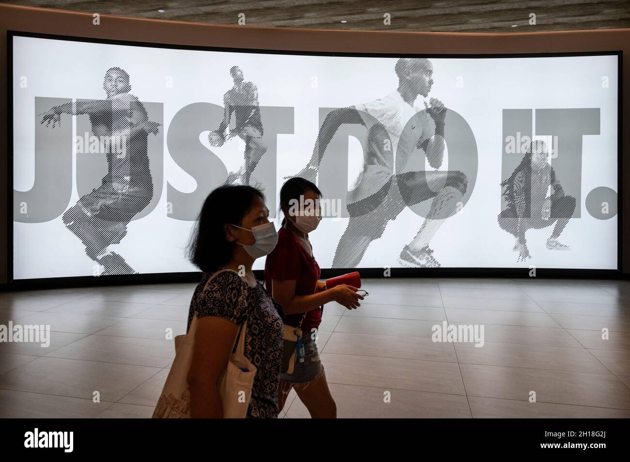 Shoppers walk past the American multinational sport clothing brand Nike  store, logo, with a slogan 