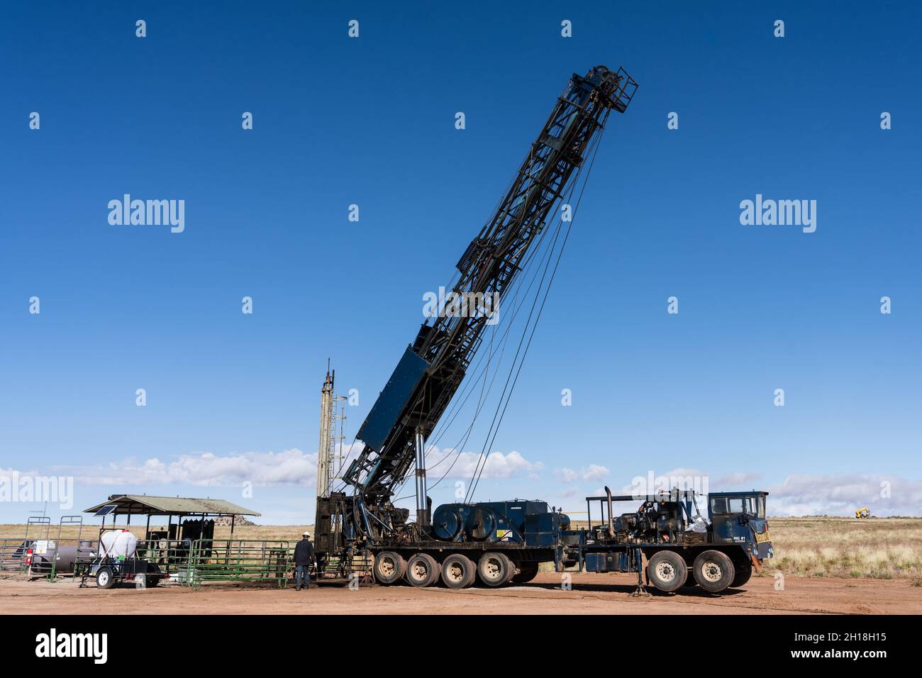 A telescoping truckmounted workover rig folding up on an oil well