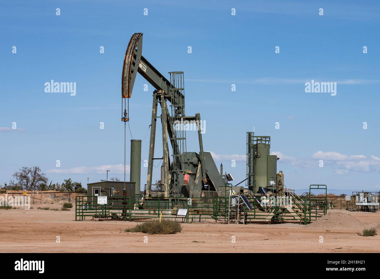 A conventional horsehead oil well pump jack unit and heater treaters on an oil well site in Utah. Stock Photo