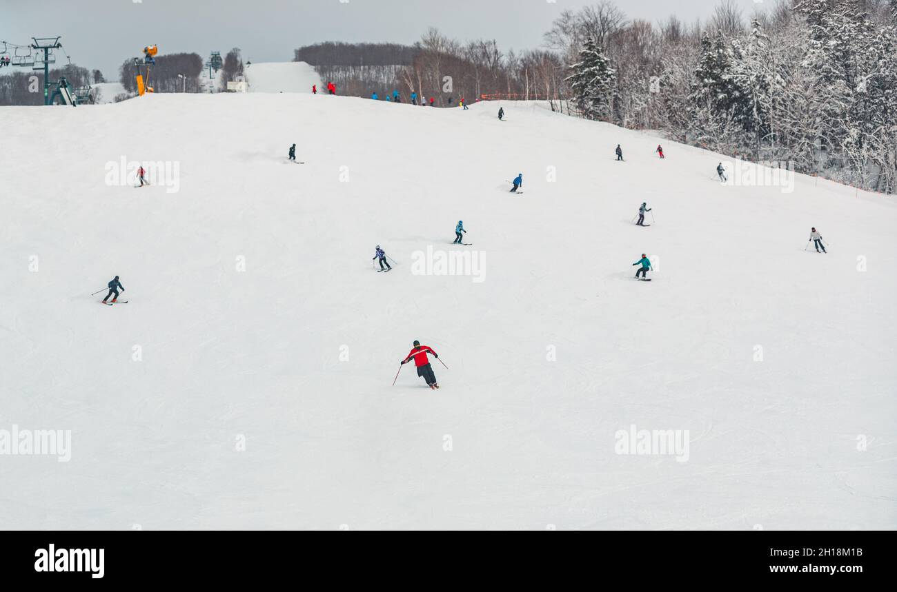 View of mountain ski slope with skiers and snowboarders going fast downhill. Alpine skiing and snowboarding, winter sports nature scenery Stock Photo
