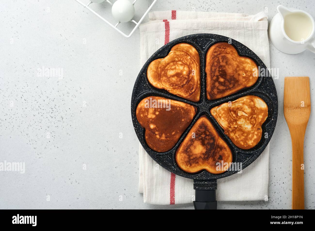 Pancakes in shape hearts with chocolate sauce in gray ceramic plate, cup of coffee on gray concrete background. Table setting for your favorite Valent Stock Photo