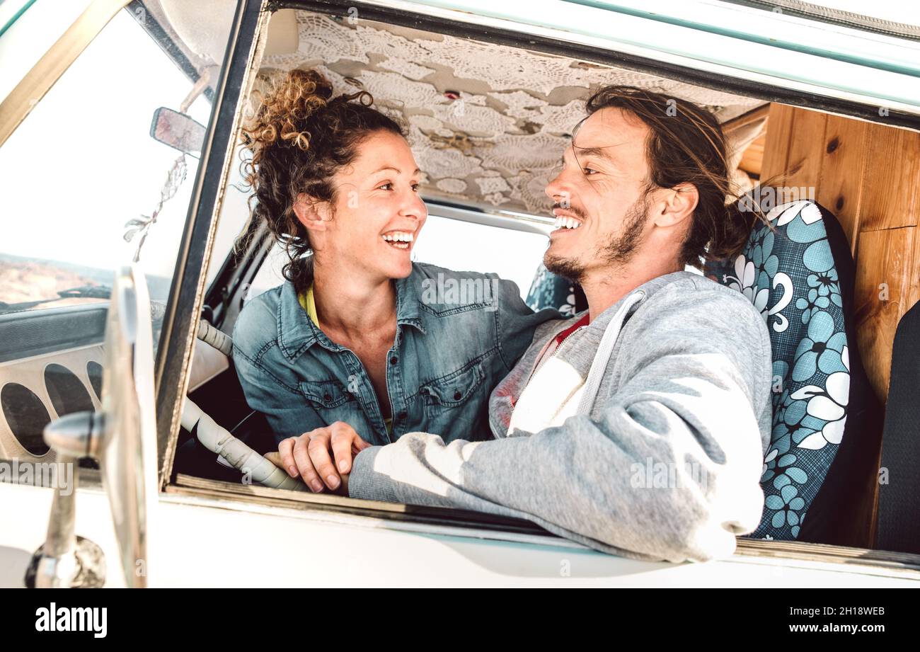 Hipster couple driving at roadtrip on oldtimer mini van transport - Travel lifestyle concept with indie people having fun in relax moment on minivan Stock Photo