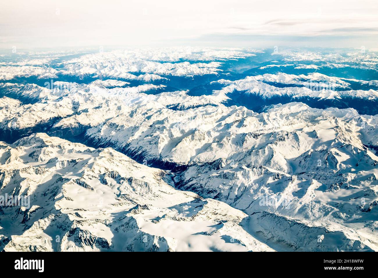 Aerial view of italian Alps with snow and misty horizon - Travel concept and winter vacation  on white snowy mountains Stock Photo