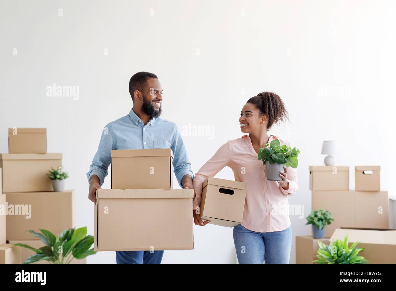 Happy young black man and woman carry cardboard boxes with things in room interior Stock Photo