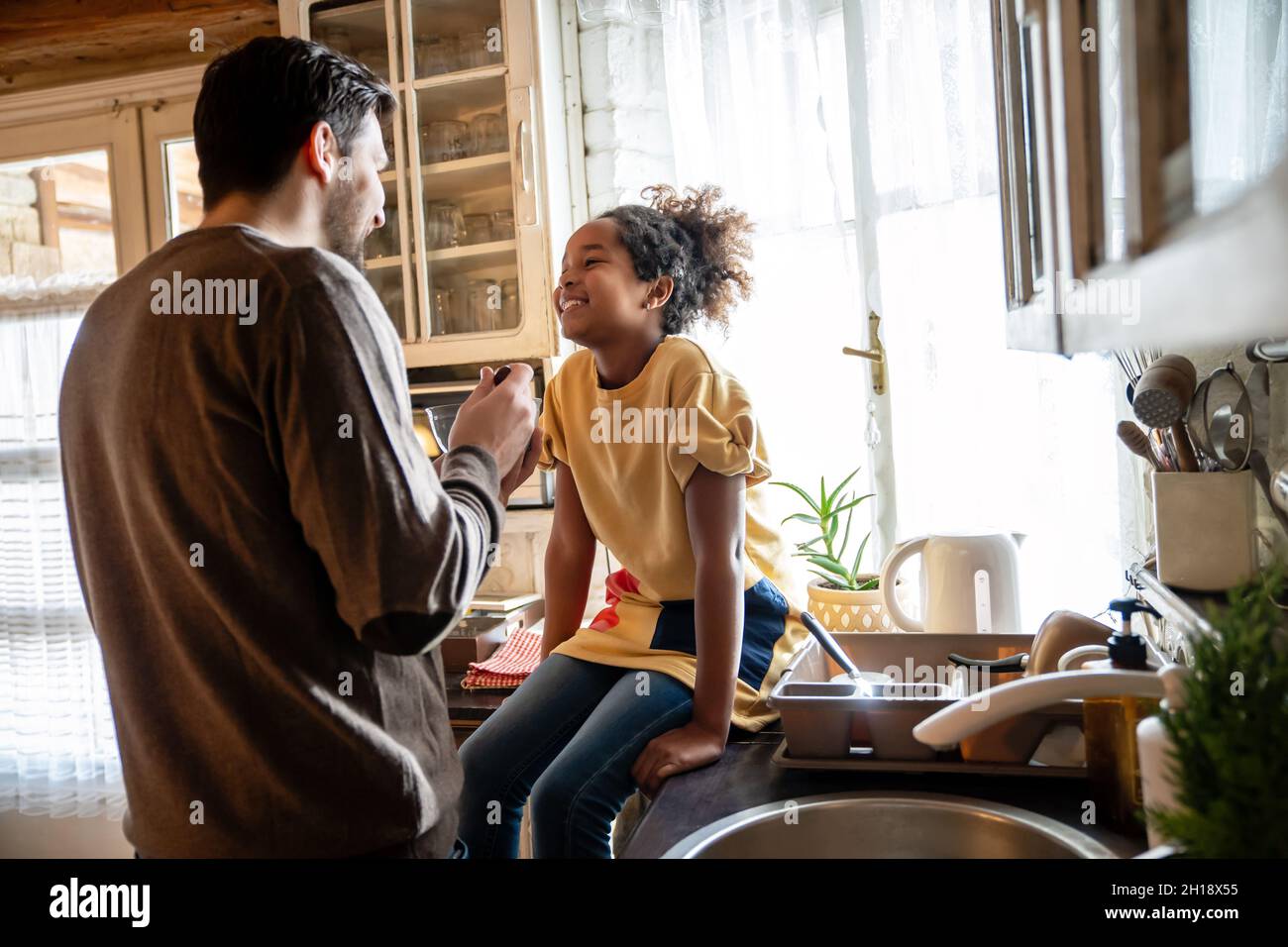 Cheerful father and his daughter having breakfast together in the kitchen Stock Photo