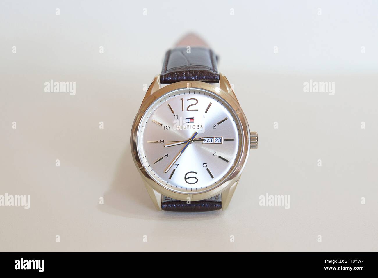 Modern fashionable Tommy Hilfiger male watch with golden details and leather strap displayed against a white background, elegant accessory for men Stock Photo