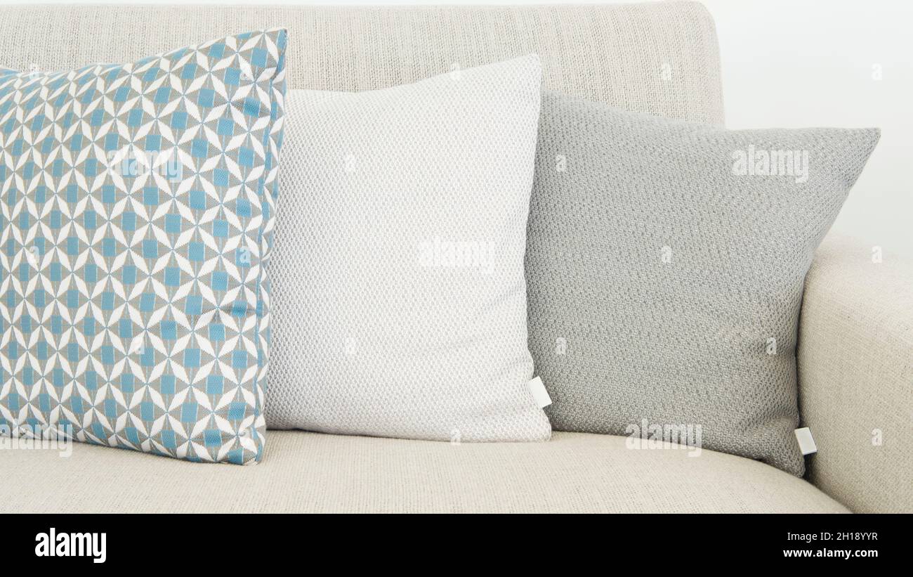 Closeup of three different sizes cushions in soft pastel colors