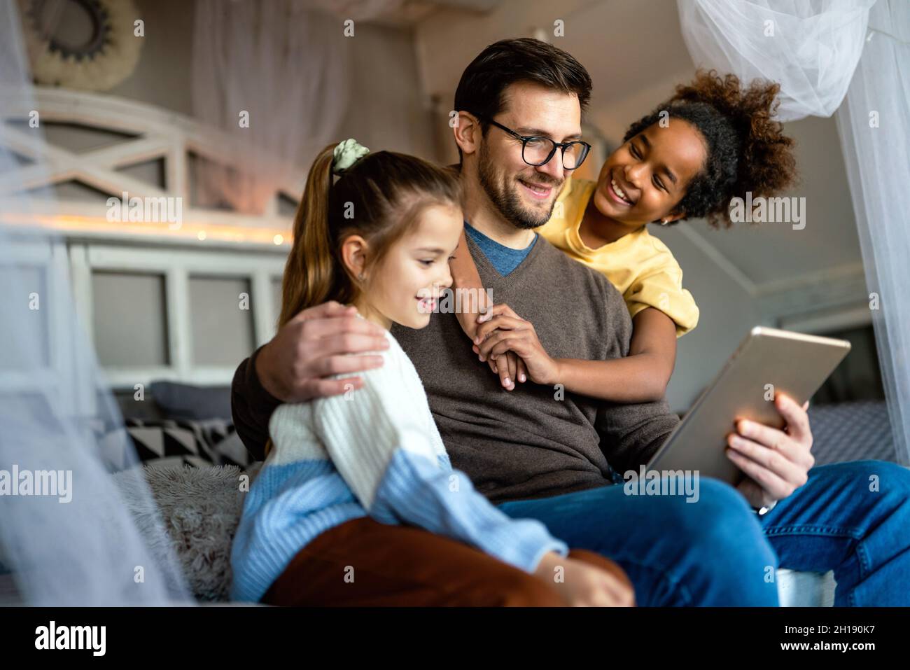 Happy father with multiethnic children playing with digital tablet at home Stock Photo
