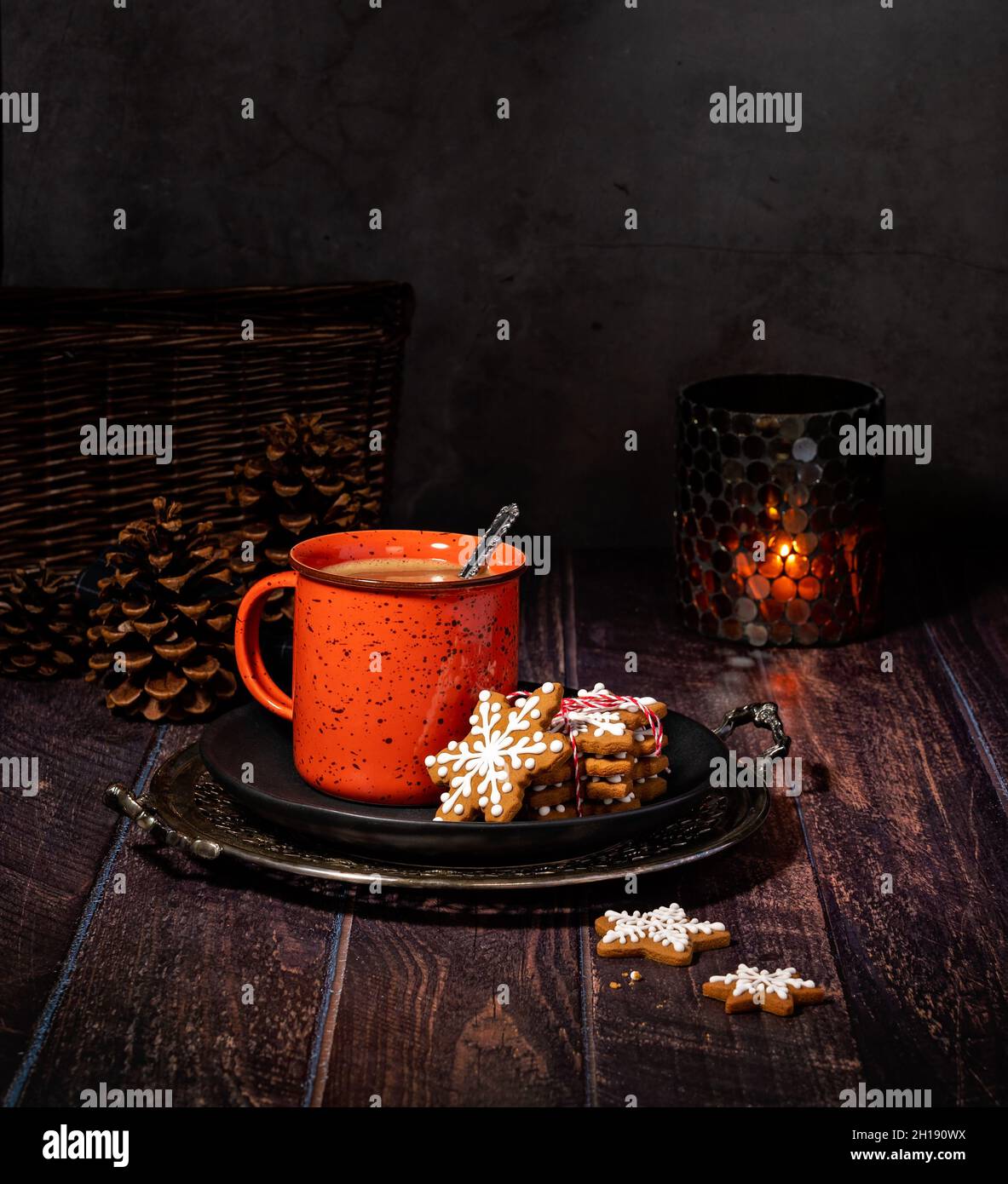 Homemade Hot Chocolate or Coffee in a Rustic Red Mug with Gingerbread Christmas Cookies on a plate as a cozy Winter treat. Stock Photo