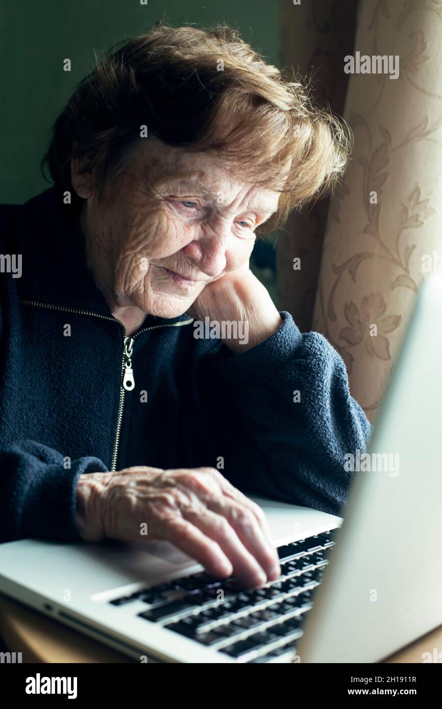 Old woman studying working on the computer in her home. Stock Photo