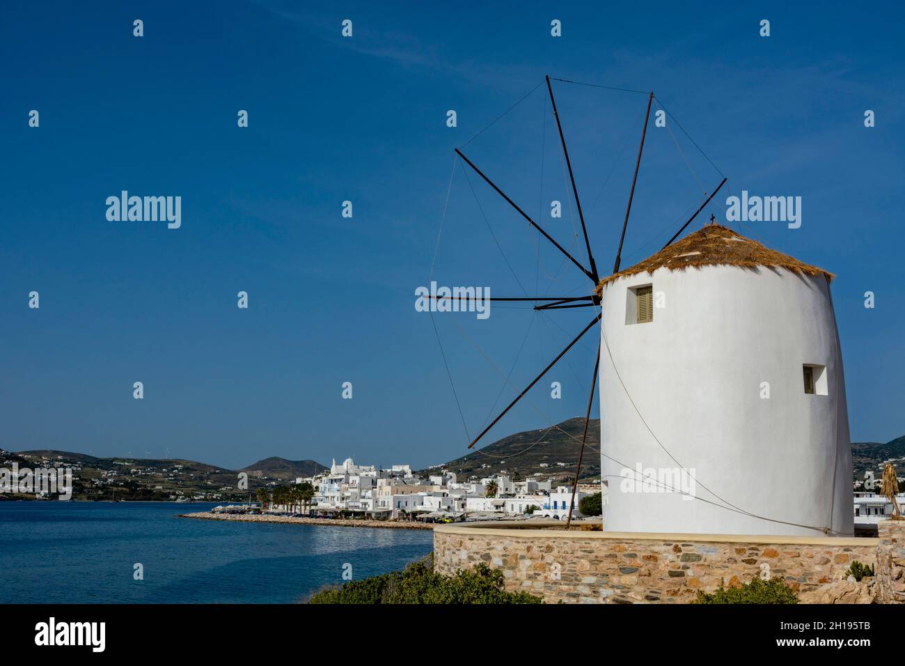 A scenic view of the Parikia waterfront and a traditional windmill ...
