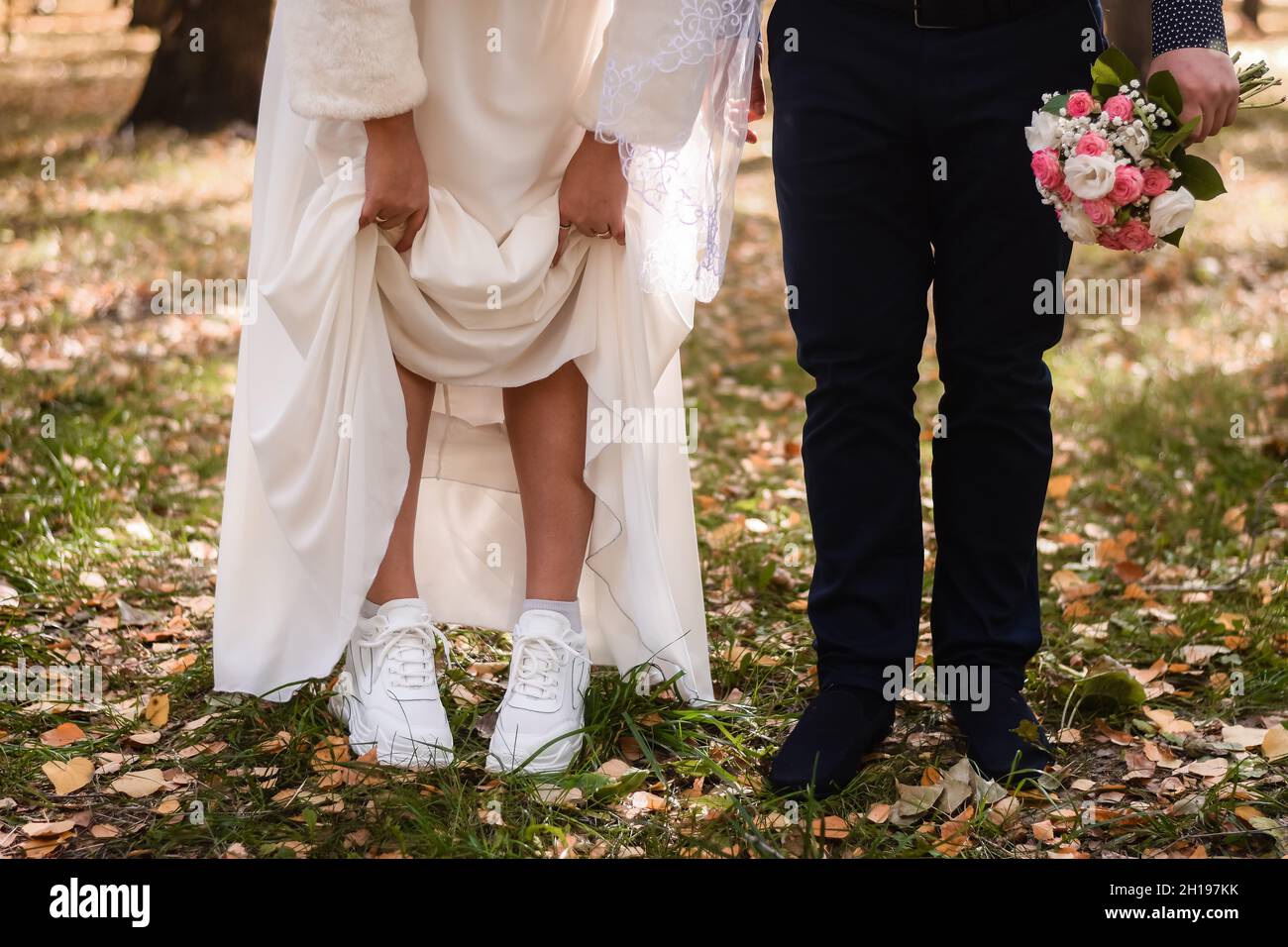 the bride lifted her skirt, showing white sneakers. Stock Photo