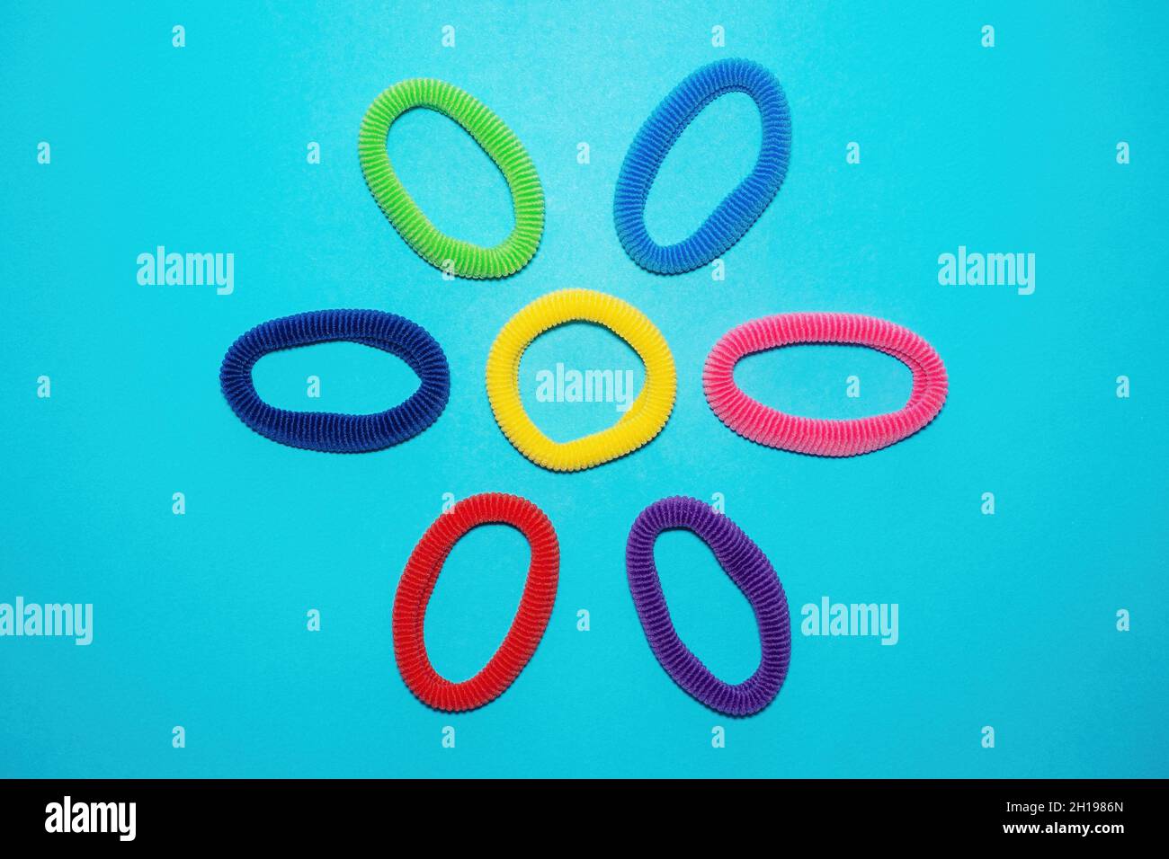 Top view of multicolored scrunchies, elastic hair ties, cotton hair ponytail holders, seamless hair bands on blue backdrop Stock Photo