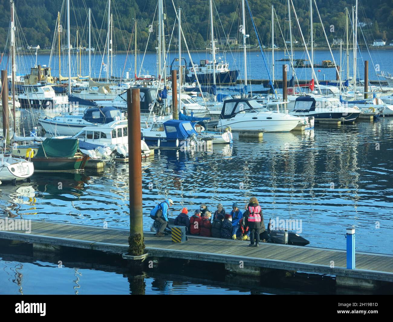 Zodiac boat with passengers moors alongside a pontoon at the marina in