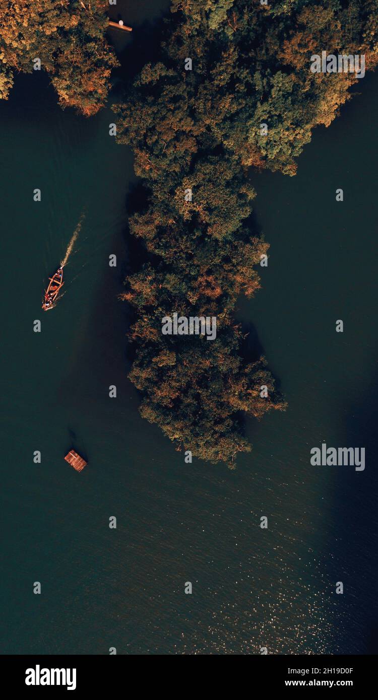 An aerial view of a lake with boats near the forest with autumn colors ...