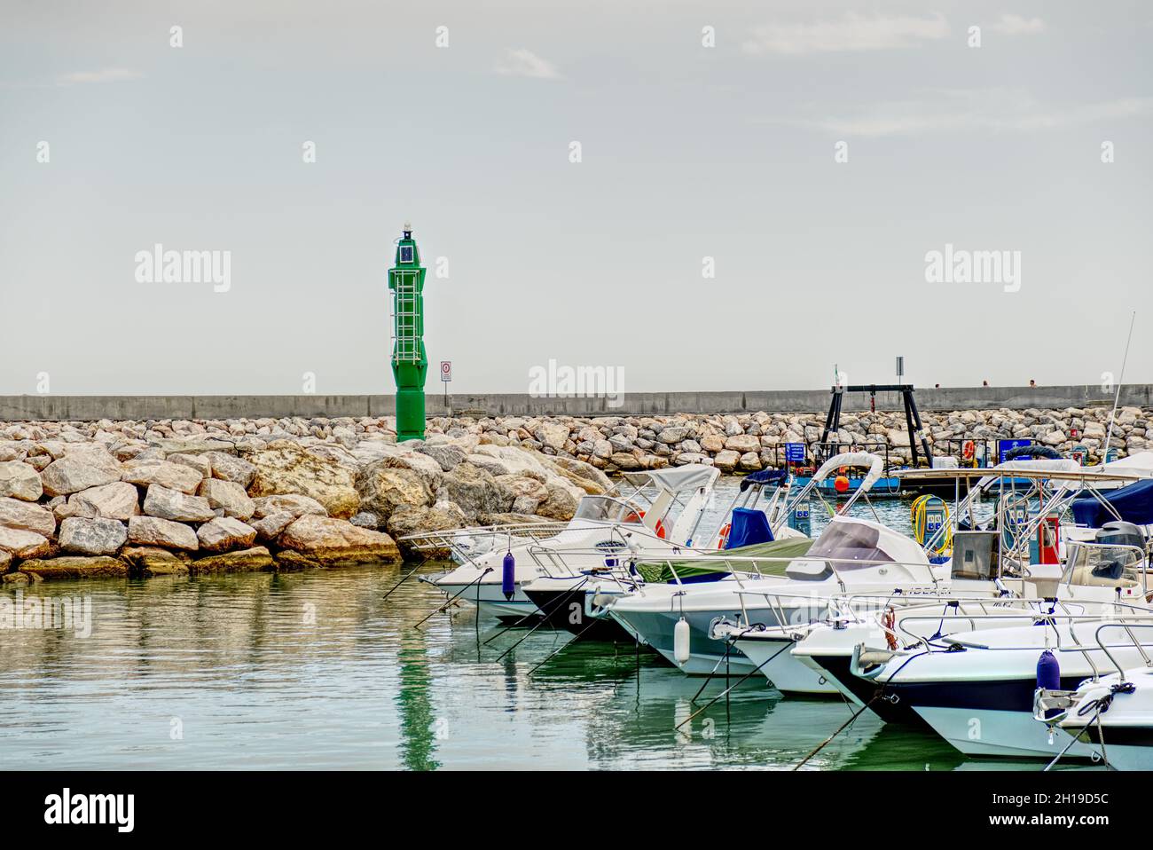 boats moored at a marina on the Mediterranean Sea with a small green ...