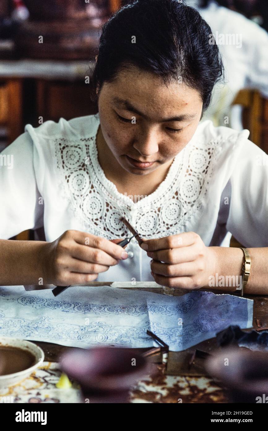 An artisan shapes a cloison or wire strip to make the design for a cloissone vase in a workshop in Beijing, China. Stock Photo